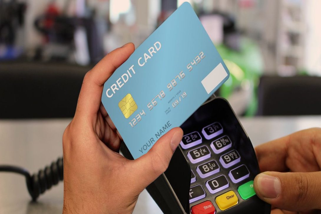 Person holding a credit card and a portable swipe machine