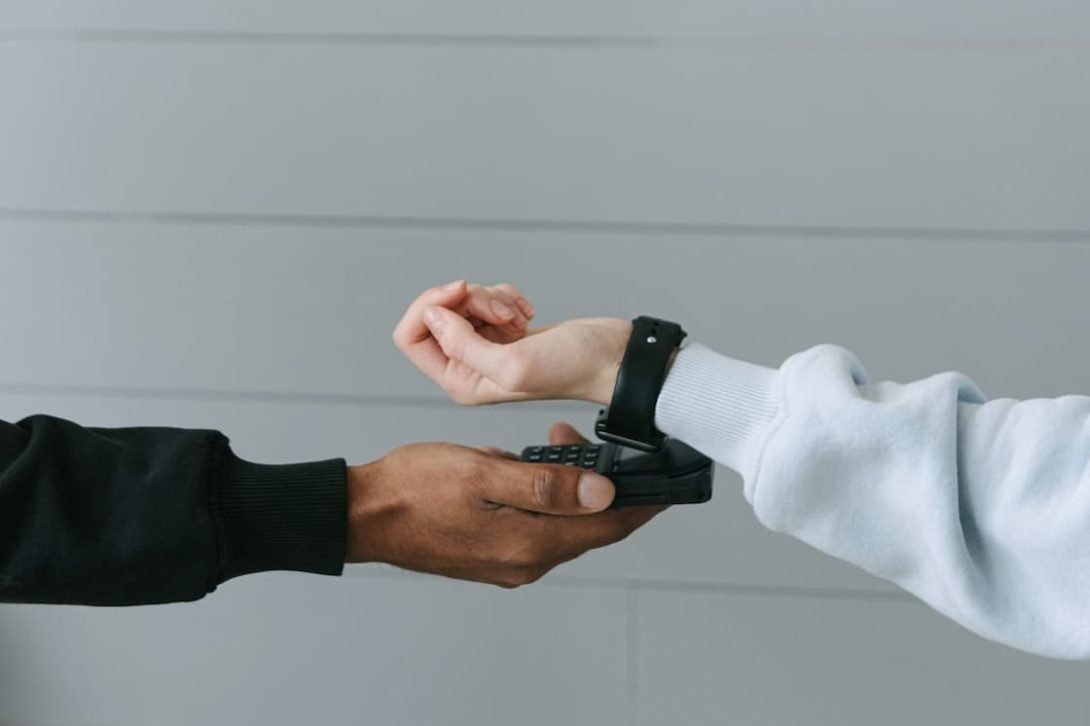 Person using his smart watch to pay for his purchases by scanning it through a pay reader