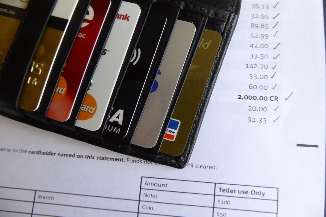 Different kinds of credit cards inserted into a wallet while it rests on top of a credit card statement