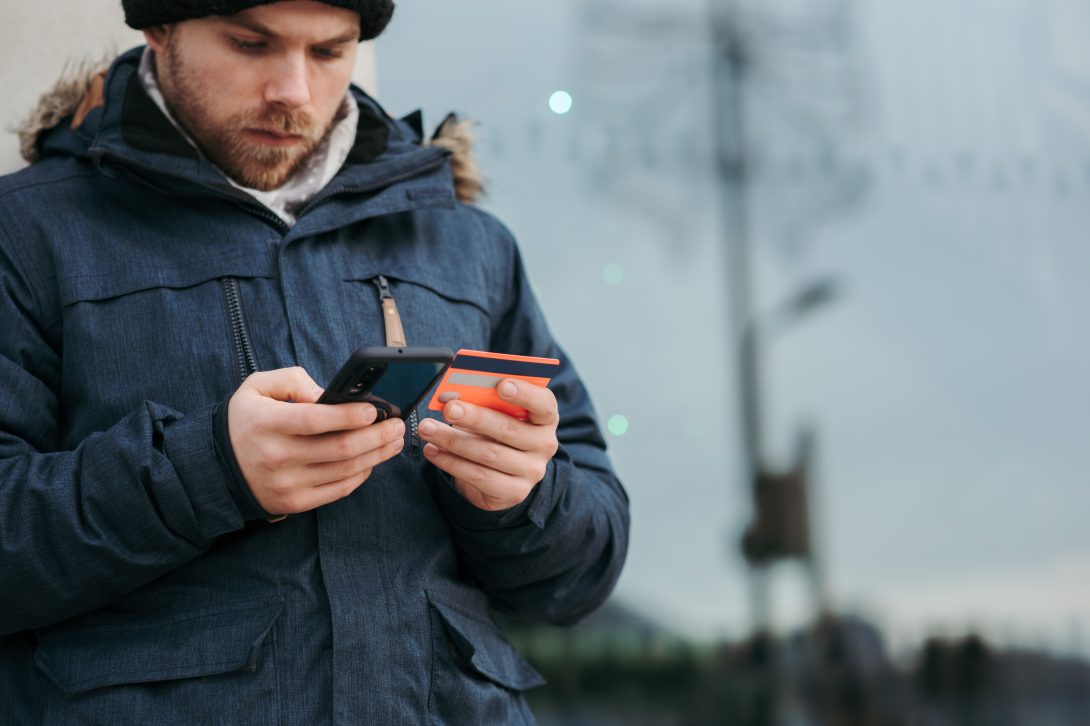 A man holding and looking at her phone and credit card