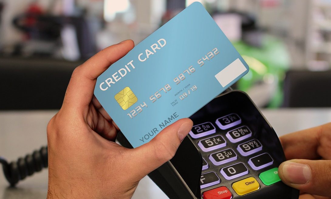 A man holding a blue credit card and a payment terminal