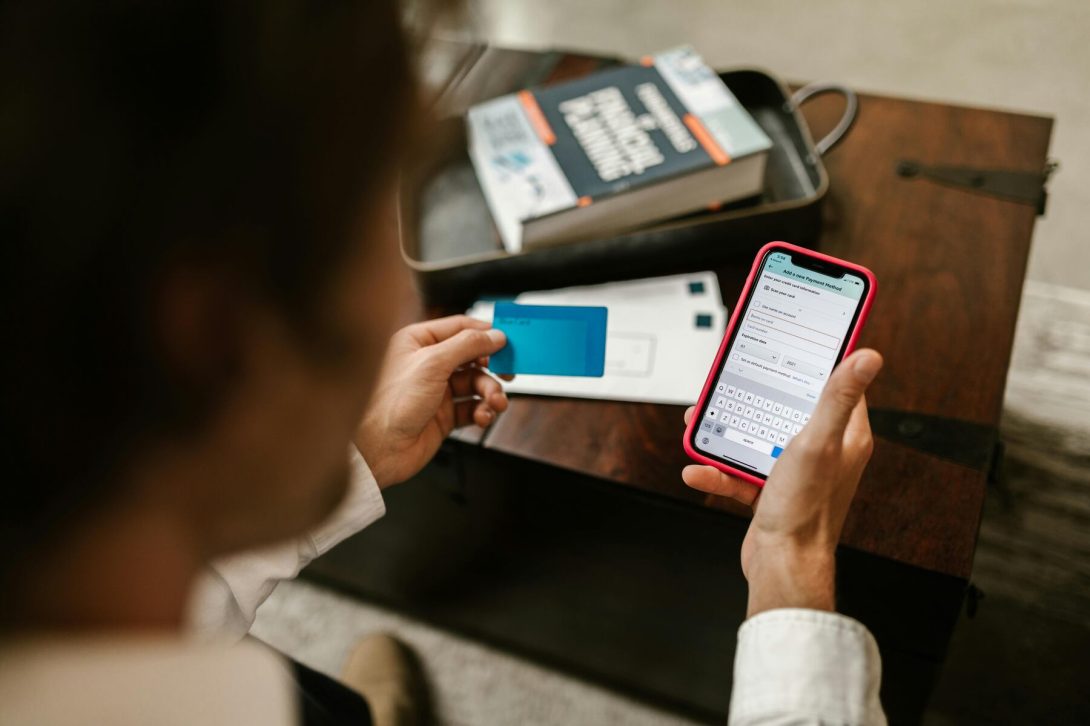 A man looking at the transaction details on his phone while holding a blue credit card