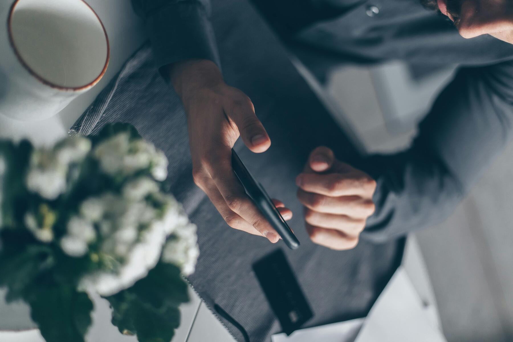 A man holding his phone and his credit card on his lap