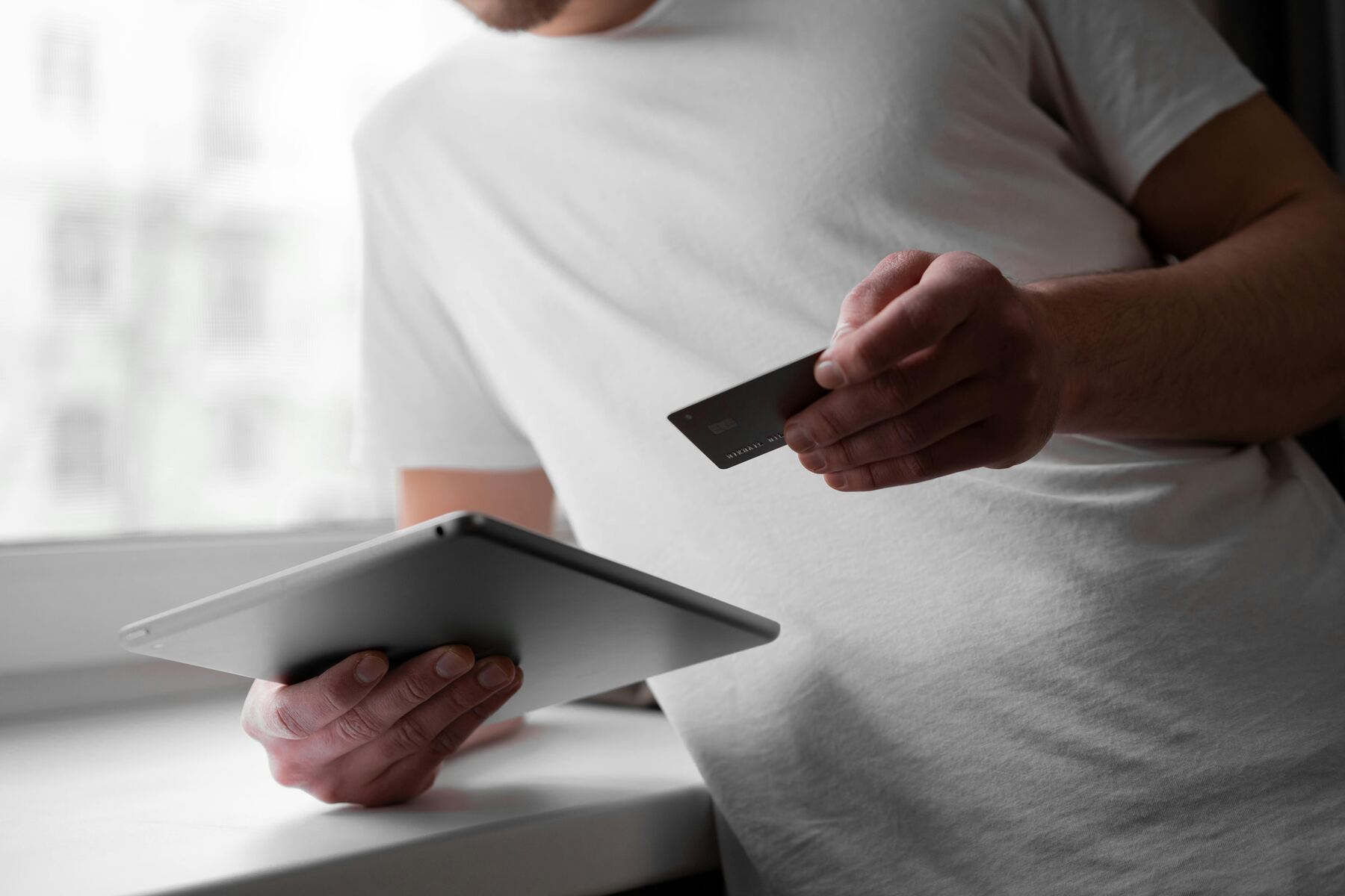 A man holding a tablet and a credit card