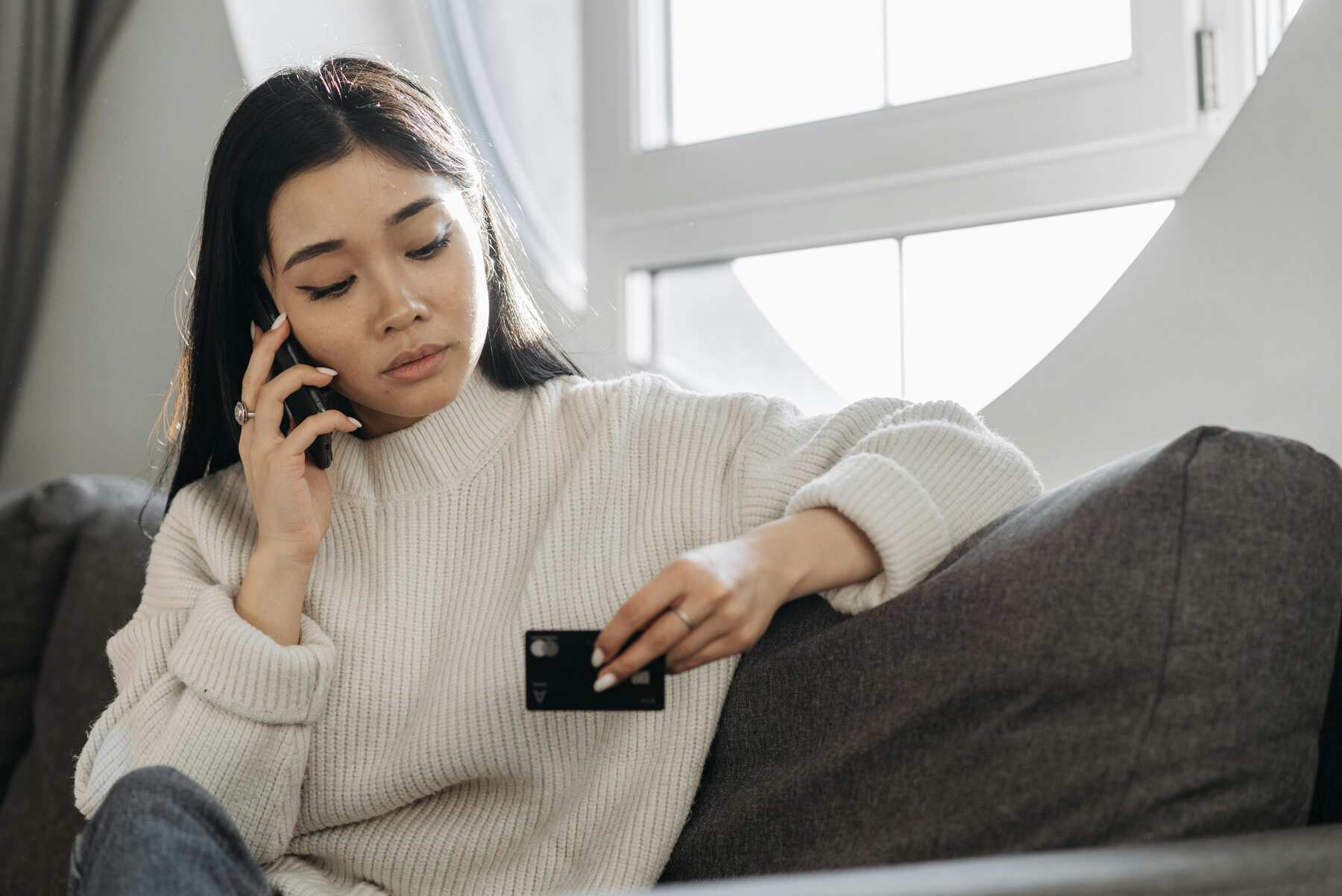 A woman calling someone on the phone while holding a credit card