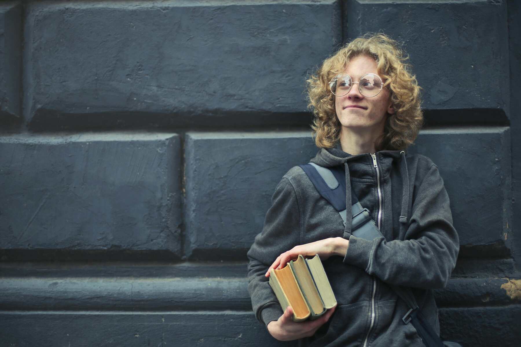 A college student holding three thick books