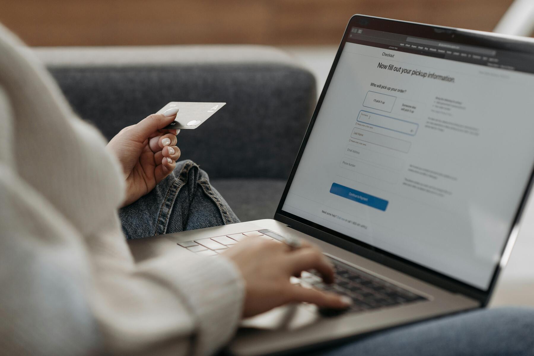 A woman typing on her laptop while holding her credit card on her other hand