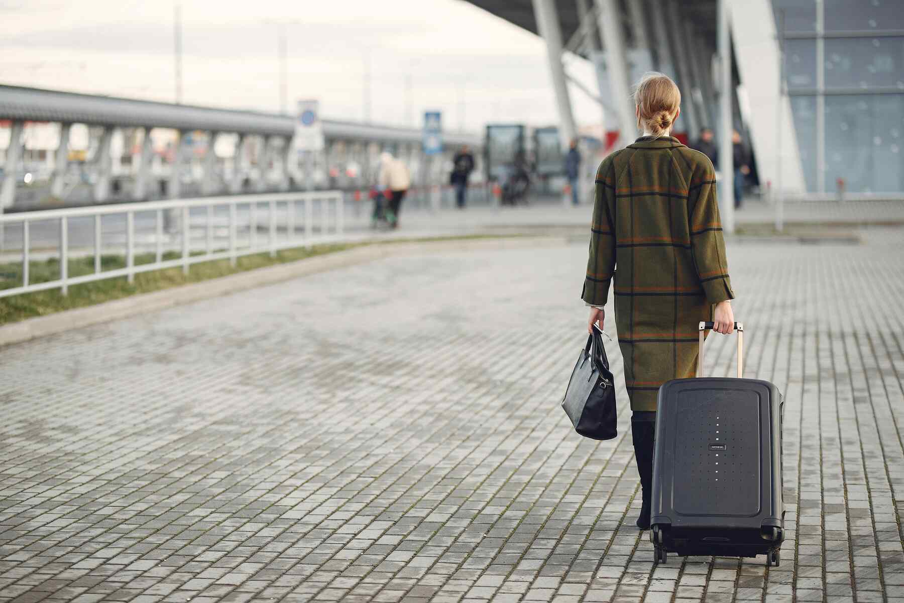 A woman outside the airport pulling her luggage