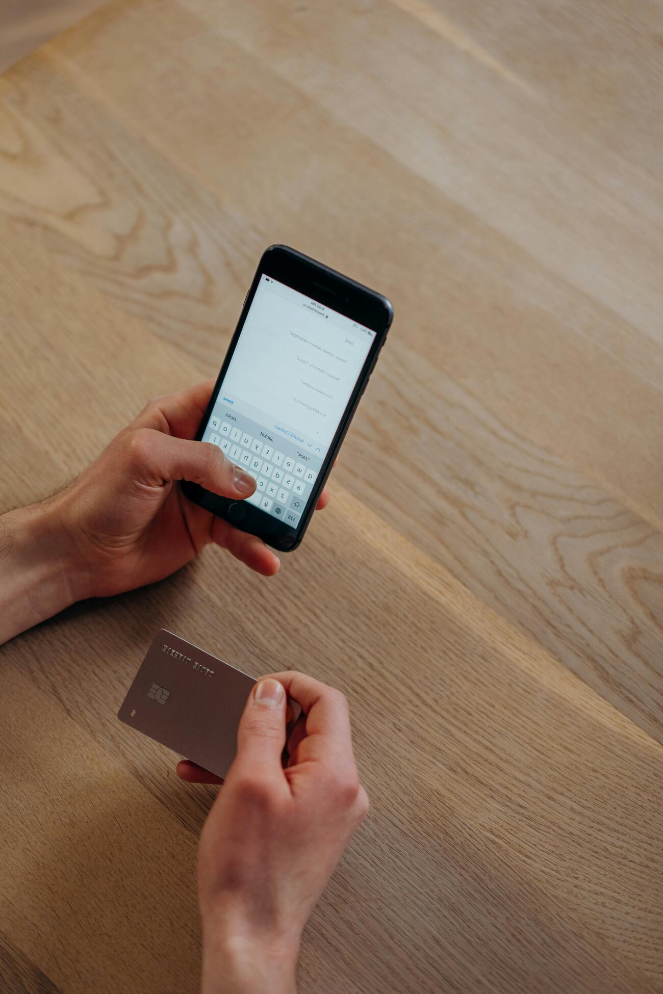 A person using a smartphone and holding a credit card