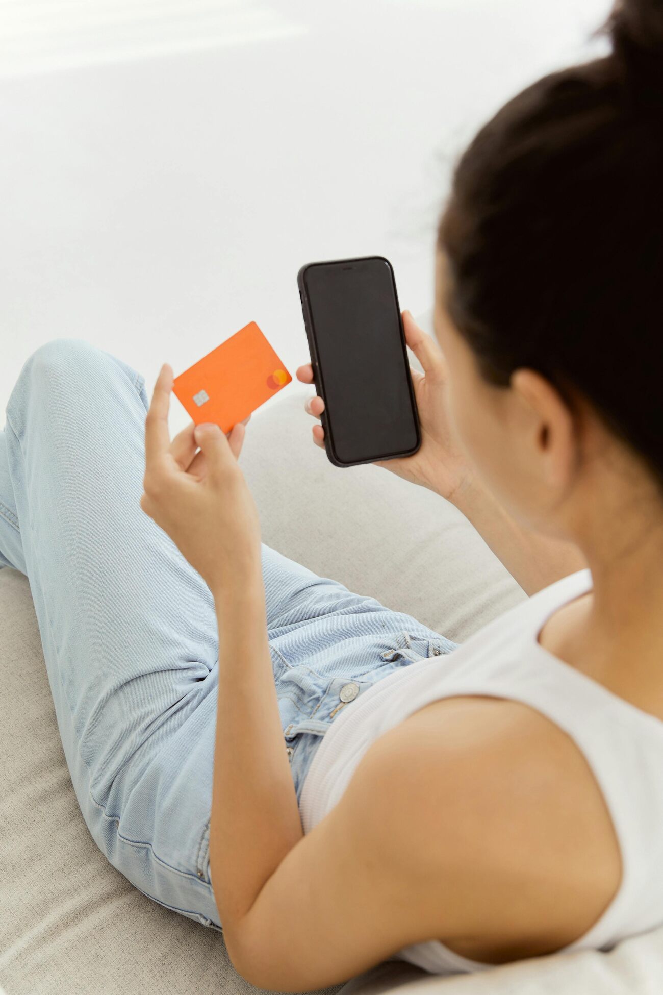 A woman holding a credit card and a mobile phone