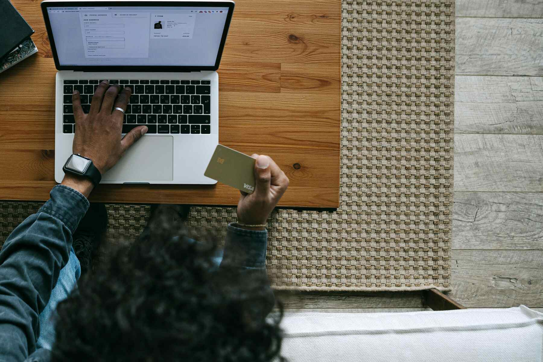 A man typing on his laptop while holding a credit card