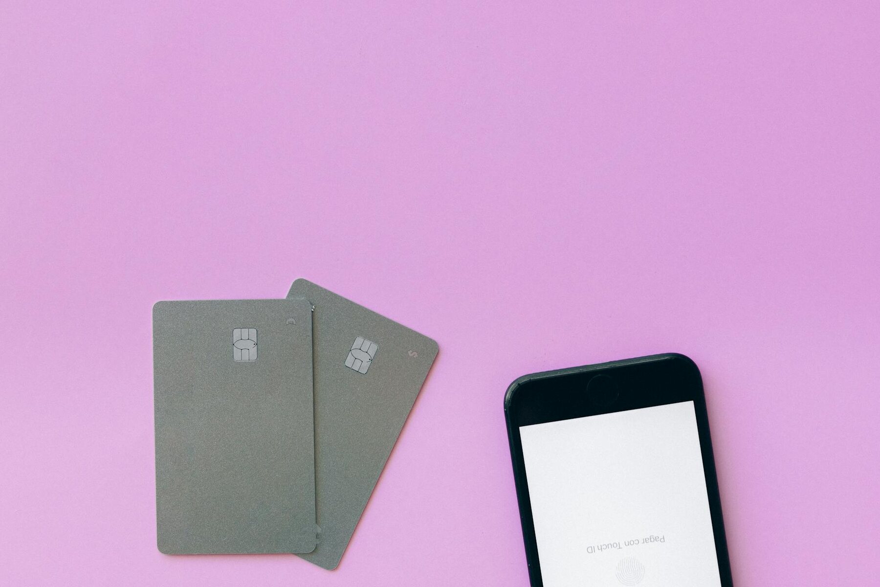 A smartphone and credit cards on a pink background